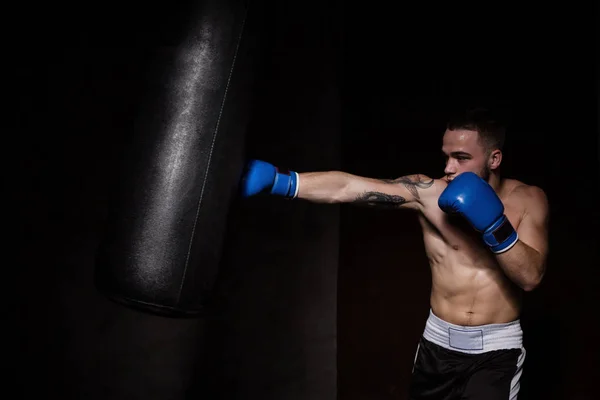 Atleta boxeador homem perfurando um saco de perfuração — Fotografia de Stock