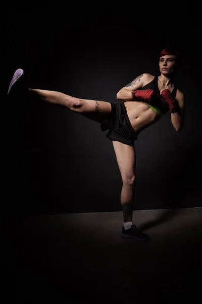 Jovem tatuado mulher chutando com a perna — Fotografia de Stock