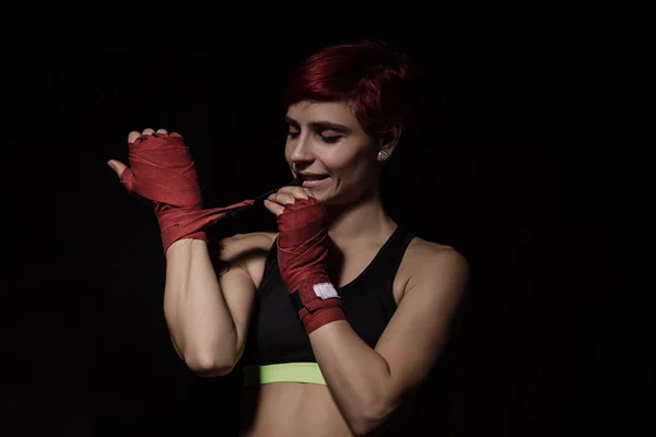 Mulher está enrolando as mãos com envoltórios de boxe vermelho — Fotografia de Stock