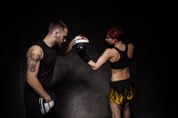 Женщина-боксер в тренировочных перчатках провела тренера по боксу
