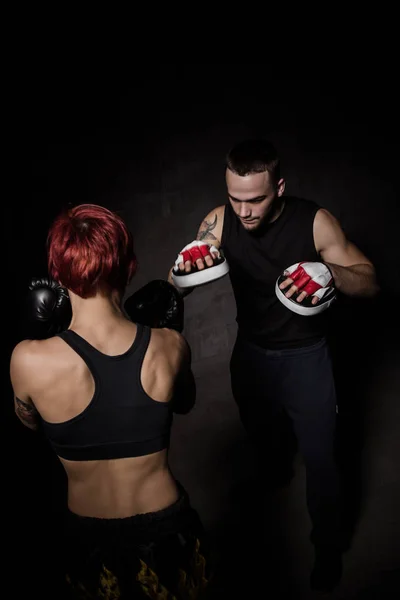 Mujer boxeadora golpeando guantes de entrenamiento sostuvo un entrenador de boxeo — Foto de Stock