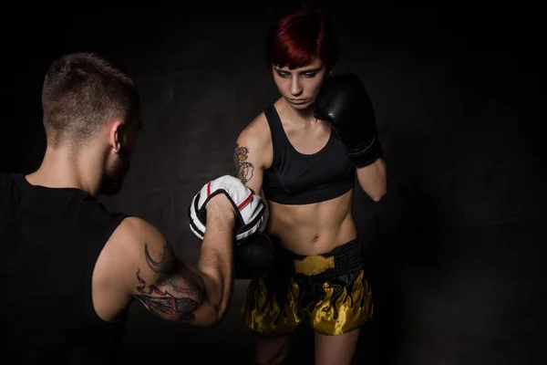 Mujer boxeadora golpeando guantes de entrenamiento sostuvo un entrenador de boxeo — Foto de Stock