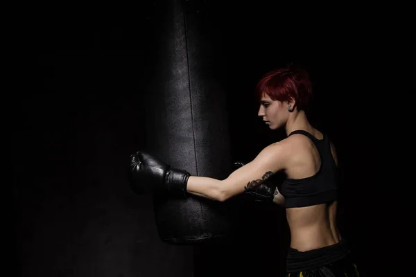Atleta boxeador mulher perfurando um saco de perfuração — Fotografia de Stock