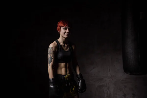 Sorrindo jovem mulher de boxe no quarto escuro — Fotografia de Stock