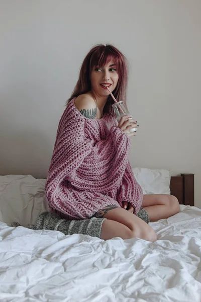 Hermosa mujer joven en suéter de gran tamaño rosa en la cama —  Fotos de Stock