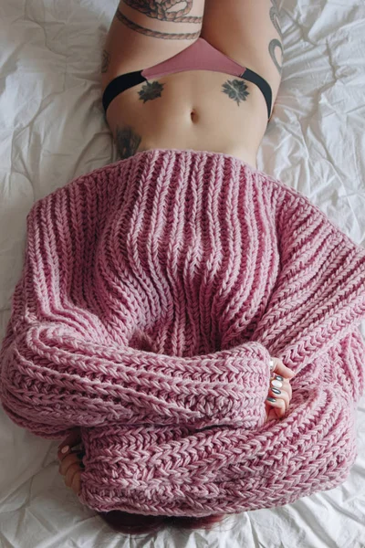 Belle jeune femme en pull oversize rose au lit — Photo