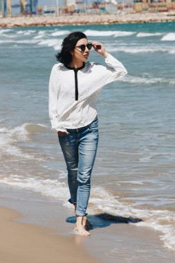 Kumsalda yürüyen güzel genç bir kadın.