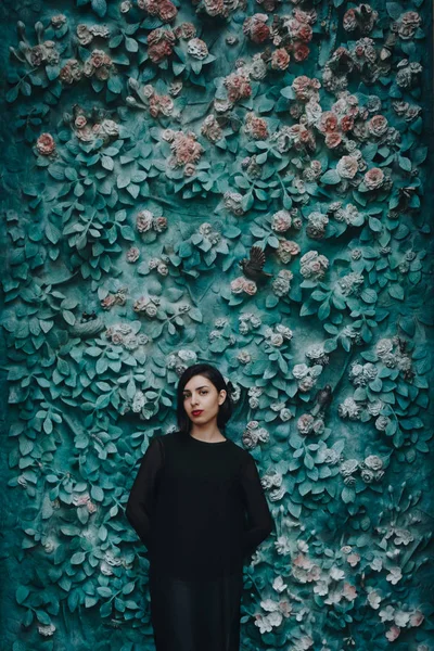 검은 드레스 꽃과 녹색 벽 근처에서 젊은 여자 — 스톡 사진