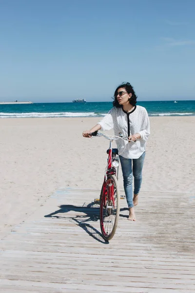 Mujer joven feliz con bicicleta en una playa — Foto de Stock