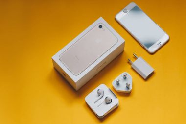 Sarı arka plan üzerinde iPhone 7 şarj cihazı ve kutusu ile Üstten Görünüm