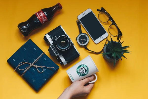 Mão segurando Starbucks copo com objetos diferentes para viajar — Fotografia de Stock