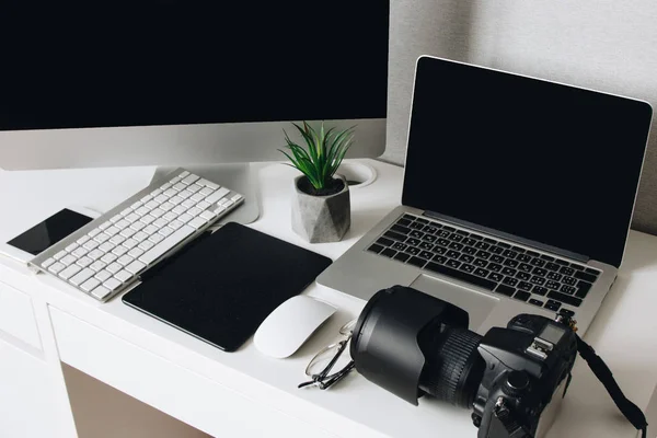 Mesa de trabalho de fotógrafo com câmera, laptop, tablet e computador — Fotografia de Stock