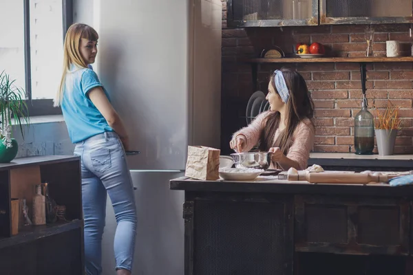 Mujer joven con su hermana pequeña cocinando pastel de vacaciones — Foto de Stock