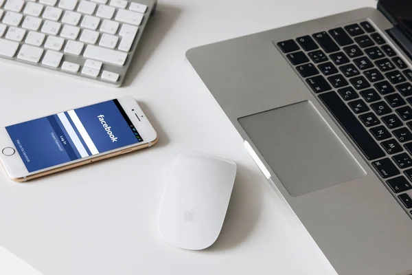Laptop, keynote e iPhone 7 com Facebook página inicial na área de trabalho branca — Fotografia de Stock
