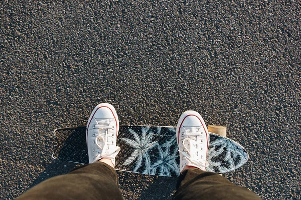 Piernas en zapatillas blancas en una tabla de skate —  Fotos de Stock