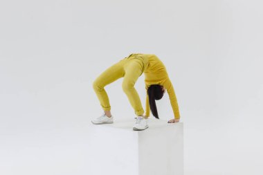 Beyaz küp üzerinde sarı giysili kadın