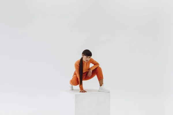 Woman in orange clothes on white cube — Stock Photo, Image