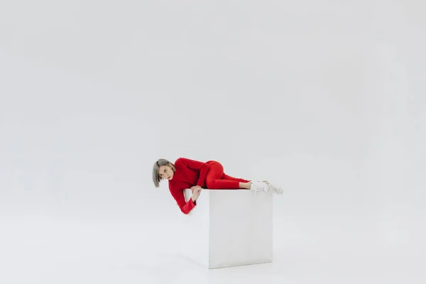 Woman in red clothes on white cube — Stock Photo, Image