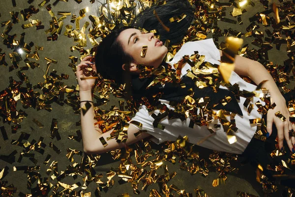 Mujer en el suelo con confeti dorado — Foto de Stock