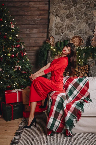 Wanita muda cantik dengan gaun merah panjang di dekat pohon Natal — Stok Foto