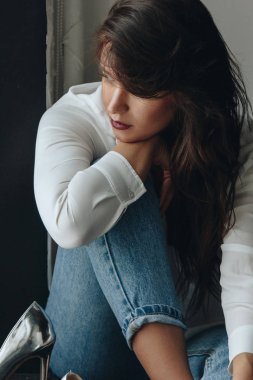 Beyaz bluz ve kot pantolon giyen güzel genç bir kadın.