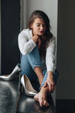 Beyaz bluz ve kot pantolon giyen güzel genç bir kadın.