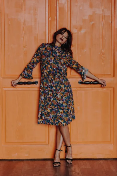 Όμορφη νεαρή γυναίκα στέκεται κοντά στην πορτοκαλί πόρτα — Φωτογραφία Αρχείου