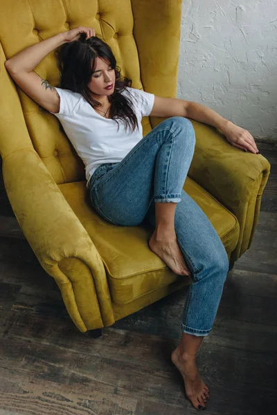 Hermosa joven sentada en un sillón amarillo — Foto de Stock