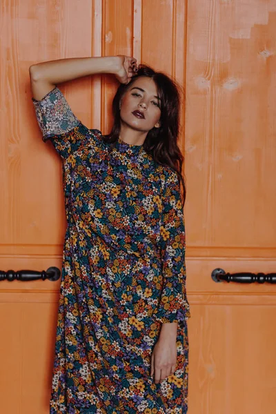 Schöne junge Frau steht neben der orangefarbenen Tür — Stockfoto