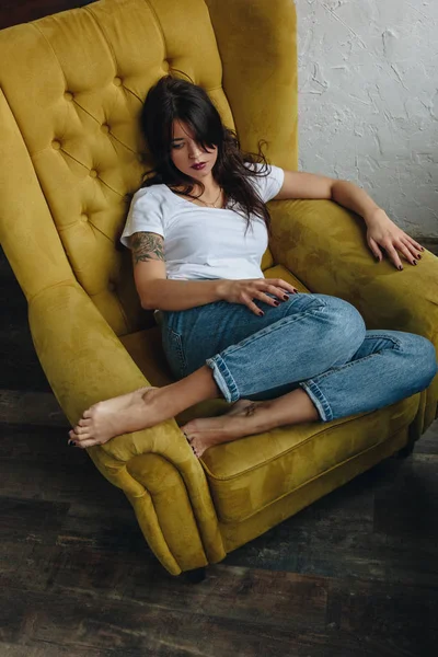 노란 안락의자에 앉아 있는 아름다운 소녀 — 스톡 사진