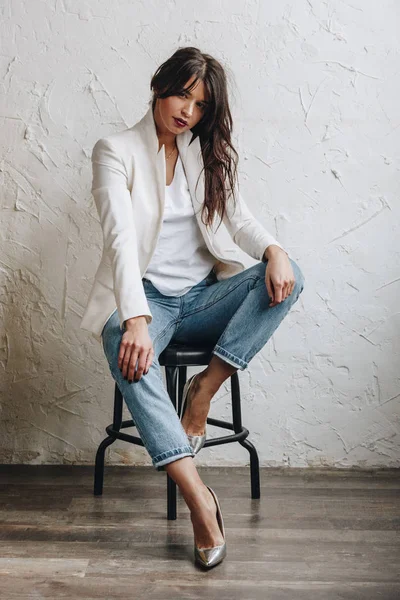Wanita muda cantik mengenakan blazer putih dan celana jeans biru — Stok Foto