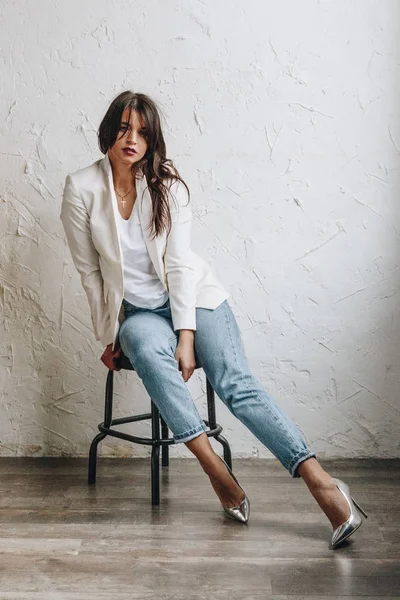 Wanita muda cantik mengenakan blazer putih dan celana jeans biru — Stok Foto