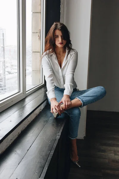 Piękna młoda kobieta w białej bluzce i niebieskich dżinsach — Zdjęcie stockowe