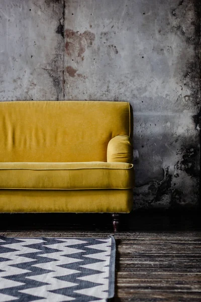 Sofá amarelo contra a parede cinza — Fotografia de Stock