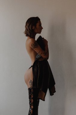Siyah bikini ve deri ceket giyen dövmeli seksi bir kadın.