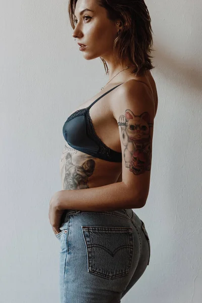 Sexy woman with tattoos wearing black lingerie and jeans