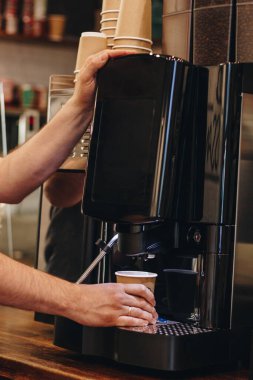 Barmen kafede kahve makinesiyle kahve yapıyor.
