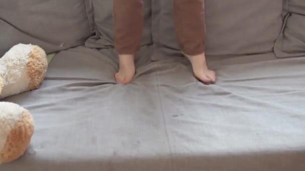 Мальчик прыгает на диване дома — стоковое видео