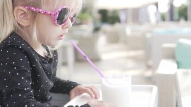 Şık küçük sarışın kız bir yaz kafesinde milkshake içiyor..