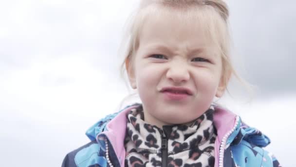 Красива маленька дівчинка їсть яблуко на відкритому повітрі восени — стокове відео