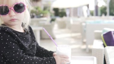 Modaya uygun bir bebek açık bir kafede pipetten vanilyalı milkshake içer..