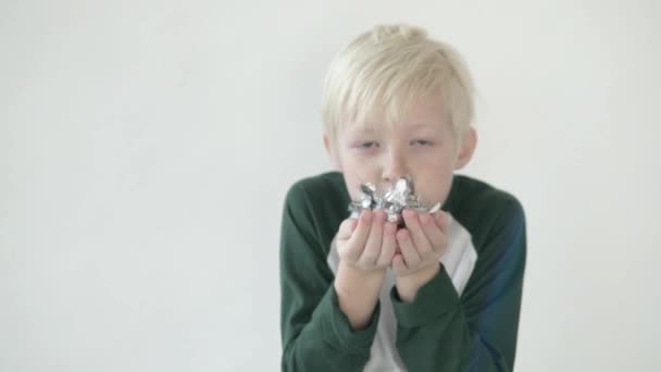 Küçük çocuk beyaz arka planda bir stüdyodan konfeti üflüyor. — Stok video
