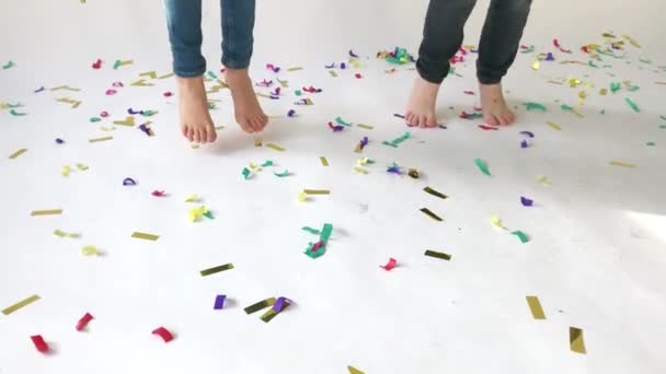 Kinderen voeten springen op een vloer bezaaid met gekleurde confetti — Stockvideo