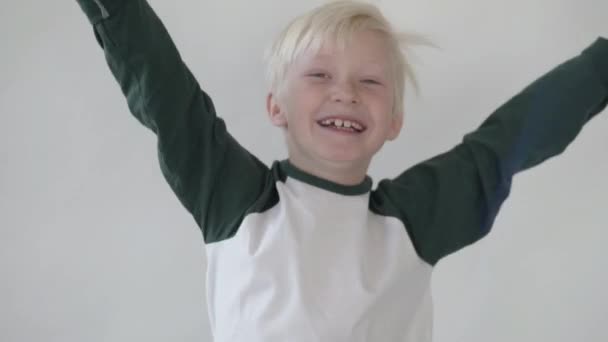 Το χαρούμενο αγόρι πηδάει και σηκώνει τα χέρια ψηλά. — Αρχείο Βίντεο