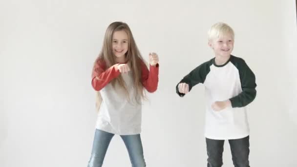 Elegante niño y niña bailando sobre un fondo blanco — Vídeo de stock