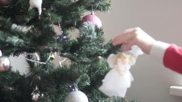 Ein Kind schmückt den Weihnachtsbaum mit einem Spielzeug. — Stockvideo