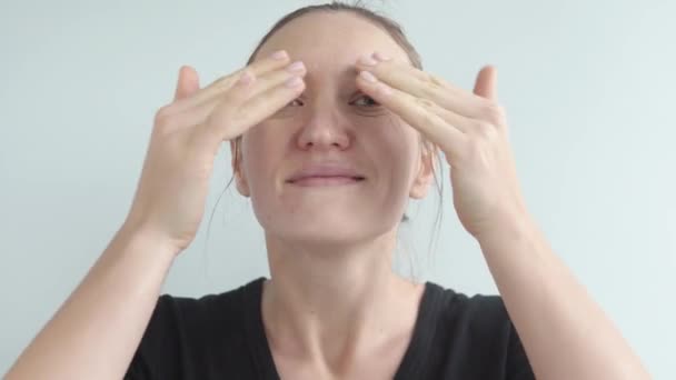 A beautiful woman applies anti-wrinkle moisturizing oil to her skin. — Stockvideo