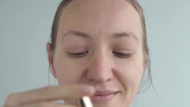 A woman paints her eyes with black mascara — Stockvideo