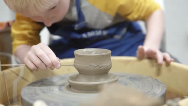 Boy blond makes a cup of clay on a potters circle — Stock Video