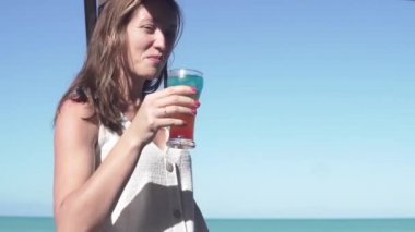 Bir bayan turist Küba 'da deniz kenarında bir barda kokteyl içiyor.